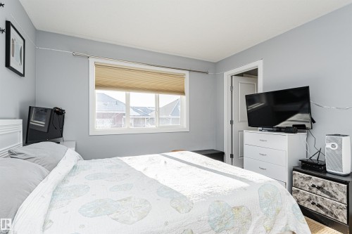 Light-filled room featuring a white window frame, neutral-toned walls, a white paneled door, and a textured window blind - 35 675 Albany Way, Edmonton, AB 