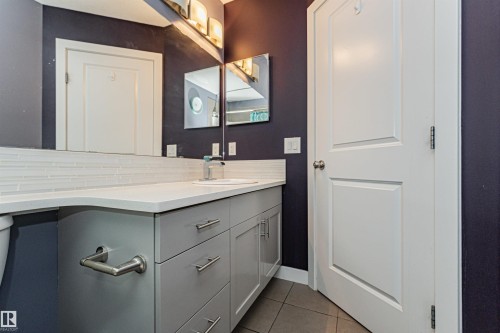 Bathroom vanity featuring a light gray cabinet with brushed nickel hardware, white countertop, and white subway tile backsplash - 35 675 Albany Way, Edmonton, AB 