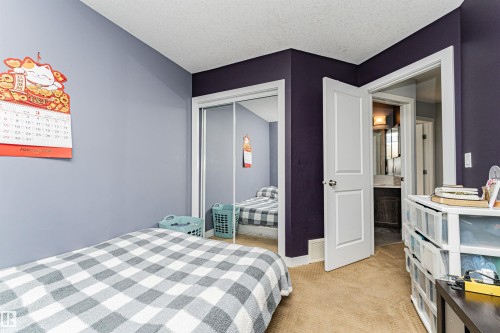 Carpeted room featuring a mirrored closet, white trim, and a white interior door - 35 675 Albany Way, Edmonton, AB 