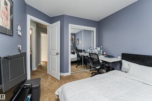 Bedroom featuring soft blue walls, light brown carpet flooring, and a white six-panel door - 35 675 Albany Way, Edmonton, AB 