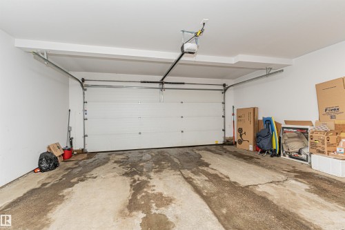 Expansive garage space featuring a white sectional garage door, exposed metal track system, and an automatic garage door opener - 35 675 Albany Way, Edmonton, AB 