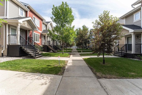 Pedestrian-friendly concrete walkway bordered by manicured lawns and mature trees - 35 675 Albany Way, Edmonton, AB 