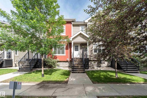 Townhome exterior featuring red and beige siding, white trim, and stone accents - 35 675 Albany Way, Edmonton, AB 