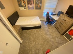 Bedroom with carpet flooring, an office area, and a baseboard heating unit - 