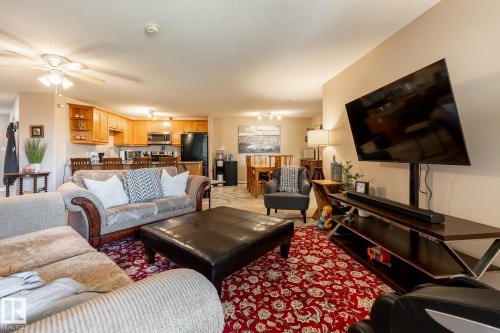 Open-concept living space featuring wood-finish cabinetry, a breakfast bar, stainless steel appliances, and ceiling fan - 330 1520 Hammond Gate Gate, Edmonton, AB 