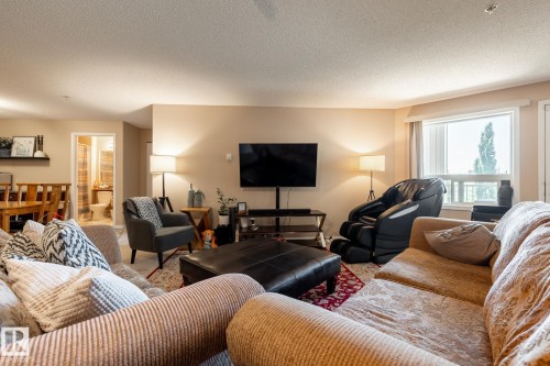 Open-concept living space featuring neutral wall tones, a large window with natural light, and recessed ceiling lighting - 330 1520 Hammond Gate Gate, Edmonton, AB 
