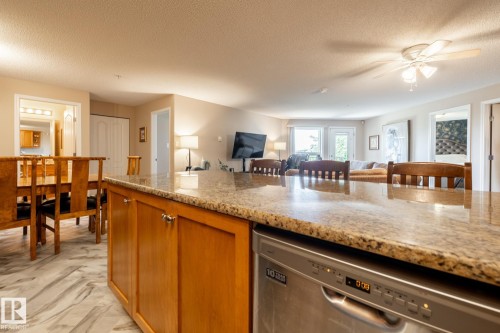 Kitchen island with granite countertop and integrated stainless steel dishwasher - 330 1520 Hammond Gate Gate, Edmonton, AB 