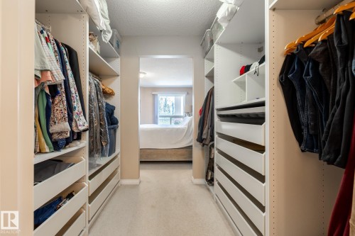 Walk-through closet featuring built-in shelving, integrated drawers, hanging rods, and light-colored carpeting - 330 1520 Hammond Gate Gate, Edmonton, AB 