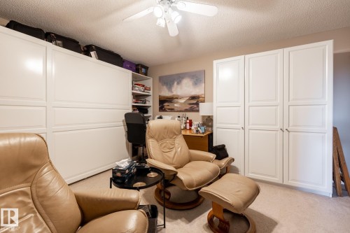 Room featuring extensive built-in white cabinetry, integrated shelving, and a ceiling fan - 330 1520 Hammond Gate Gate, Edmonton, AB 