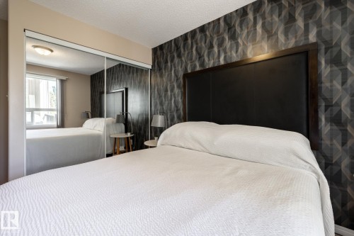 Mirrored sliding closet doors with an overhead light fixture, a window with blinds, and a feature wall with geometric pattern wallpaper - 330 1520 Hammond Gate Gate, Edmonton, AB 