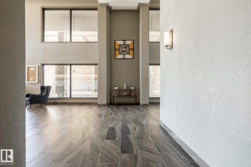 Two-story interior space featuring large format tile flooring and tall windows with dark trim - 330 1520 Hammond Gate Gate, Edmonton, AB 