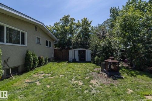 Expansive backyard with a manicured lawn, established trees, and a practical storage shed - 3608 44 Street, Leduc, AB 