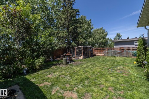 Generous backyard featuring mature trees, established shrubs, a wood fence perimeter, and a detached wooden structure - 3608 44 Street, Leduc, AB 