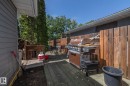 Expansive wood-plank deck featuring a privacy fence, mature perimeter trees, and a gray siding exterior - 3608 44 Street, Leduc, AB 