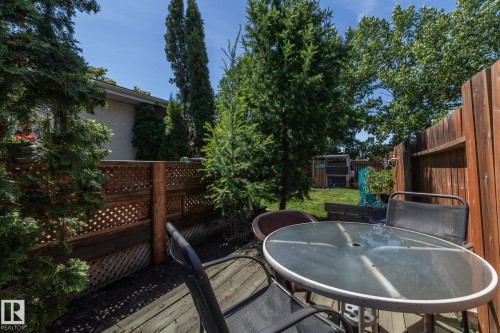 Outdoor patio featuring wood-finish decking, lattice fencing, and mature trees - 3608 44 Street, Leduc, AB 