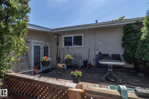 Expansive wood deck with lattice railing, featuring exterior stucco siding, white-trimmed window, and double glass-paneled French doors - 3608 44 Street, Leduc, AB 