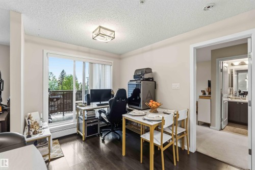 Open concept living space featuring wood-finish flooring, a contemporary ceiling light fixture, and a sliding glass door leading to an outdoor balcony - 244 1196 Hyndman Road, Edmonton, AB 