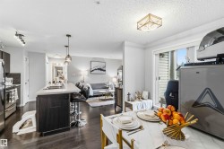 Open-concept living area featuring wood-finish flooring, a kitchen island with seating, stainless steel appliances, a sliding glass door, and recessed lighting - 