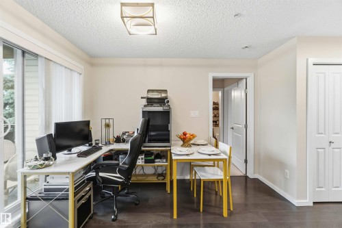 Open-concept living area with dark wood-finish flooring and a contemporary overhead light fixture - 244 1196 Hyndman Road, Edmonton, AB 
