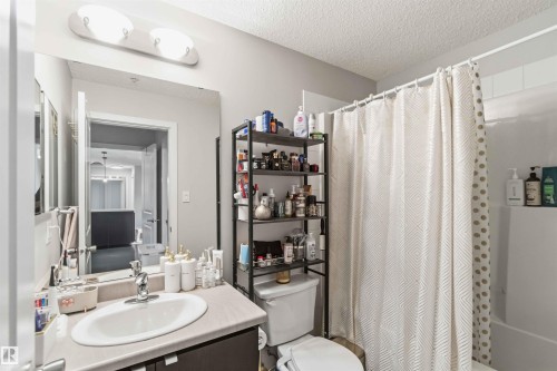 Bathroom featuring a single vanity, undermount sink, chrome faucet, and a wall-mounted mirror with overhead lighting - 244 1196 Hyndman Road, Edmonton, AB 