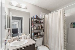 Bathroom featuring a single vanity, undermount sink, chrome faucet, and a wall-mounted mirror with overhead lighting - 