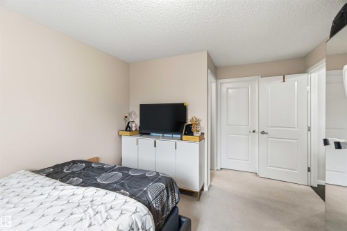 Soft neutral wall paint with textured ceiling, light-colored carpet flooring, and white paneled doors - 244 1196 Hyndman Road, Edmonton, AB 