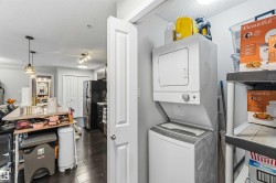 Dedicated laundry closet featuring a stacked white washer and dryer, adjacent to shelving for storage - 