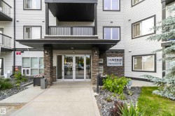Building entrance featuring a covered porch, stacked stone pillars, and double glass doors - 