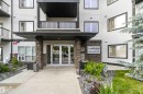 Building entrance featuring a covered porch, stacked stone pillars, and double glass doors - 244 1196 Hyndman Road, Edmonton, AB 