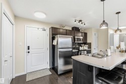 Kitchen featuring dark wood-finish cabinetry, stainless steel appliances, and a light-colored countertop with an integrated double sink - 