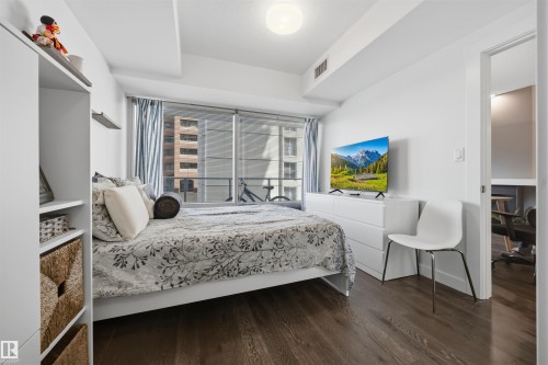 Wood-finish flooring throughout, complemented by a full-wall window with vertical blinds - 802 9720 106 Street, Edmonton, AB 
