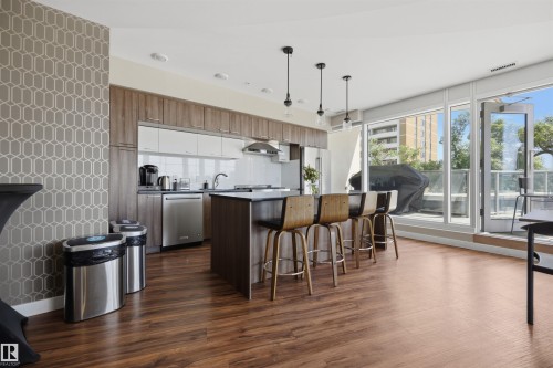 Modern kitchen featuring wood-finish flooring and a large island with seating - 802 9720 106 Street, Edmonton, AB 