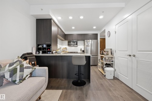 Contemporary kitchen with dark wood-finish cabinetry, stainless steel appliances, and recessed lighting - 802 9720 106 Street, Edmonton, AB 