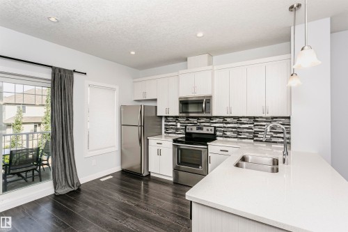Modern kitchen featuring white cabinetry and stainless steel appliances - #55 723 172 St Sw, Edmonton, AB - Indoor Photo Showing Kitchen With Double Sink With Upgraded Kitchen