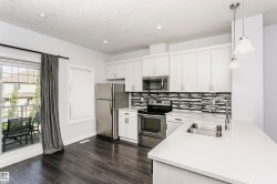 Modern kitchen featuring white cabinetry and stainless steel appliances - 