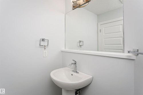 Pedestal sink with chrome faucet, large vanity mirror, and brushed nickel light fixture - #55 723 172 St Sw, Edmonton, AB - Indoor Photo Showing Bathroom