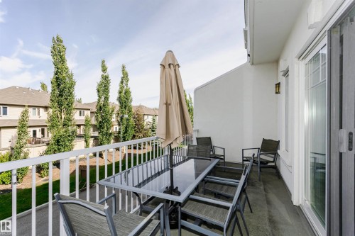 Outdoor balcony with white railing, featuring a concrete surface and a sliding glass door entry - #55 723 172 St Sw, Edmonton, AB - Outdoor With Exterior