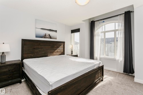 Bedroom featuring an arched window, a second window, and carpet flooring - #55 723 172 St Sw, Edmonton, AB - Indoor Photo Showing Bedroom