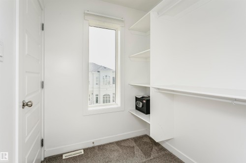 Walk-in closet featuring built-in shelving, integrated hanging rods, a window, and gray carpet flooring - #55 723 172 St Sw, Edmonton, AB - Indoor