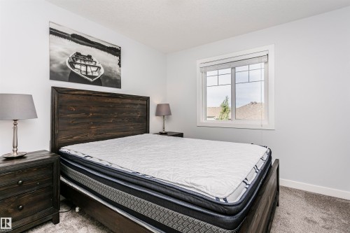 Inviting room featuring a window with white trim, light gray walls, dark wood-finish headboard, and coordinating nightstands - #55 723 172 St Sw, Edmonton, AB - Indoor Photo Showing Bedroom
