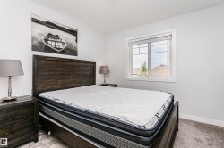 Inviting room featuring a window with white trim, light gray walls, dark wood-finish headboard, and coordinating nightstands - 