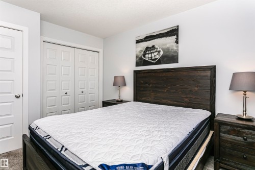 Bedroom featuring light gray wall paint, dark wood-finish headboard, and gray carpet flooring - #55 723 172 St Sw, Edmonton, AB - Indoor Photo Showing Bedroom