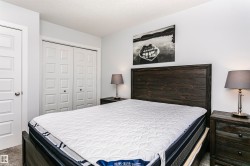 Bedroom featuring light gray wall paint, dark wood-finish headboard, and gray carpet flooring - 