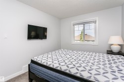 Carpeted room featuring light gray walls, a window with white trim, and a wall-mounted television - 
