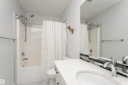Bathroom featuring a vanity with a white countertop and undermount sink, accented by a black and white mosaic tile backsplash - 