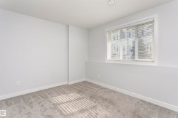 Room featuring light gray walls, gray patterned carpeting, and white trim - 