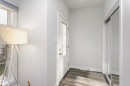 Entryway featuring a white paneled door with glass inserts, wood-finish flooring, white baseboards, and a mirrored sliding closet door - #55 723 172 St Sw, Edmonton, AB  - Indoor Photo Showing Other Room 