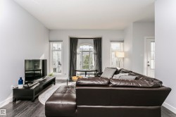 Living area featuring wood-finish flooring, light grey walls, and a prominent bay window with an arched transom - 