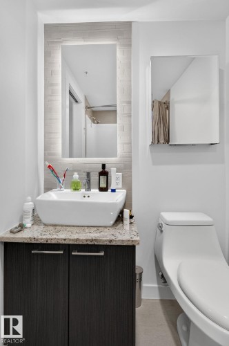 Contemporary bathroom featuring a vessel sink, integrated LED mirror, dark wood-finish vanity, light speckled countertop, and a sleek toilet - 1504 9720 106 Street, Edmonton, AB 