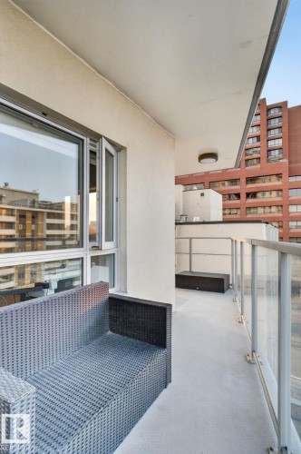 Private balcony featuring smooth stucco walls, concrete flooring, and a glass-paneled railing - 1504 9720 106 Street, Edmonton, AB 